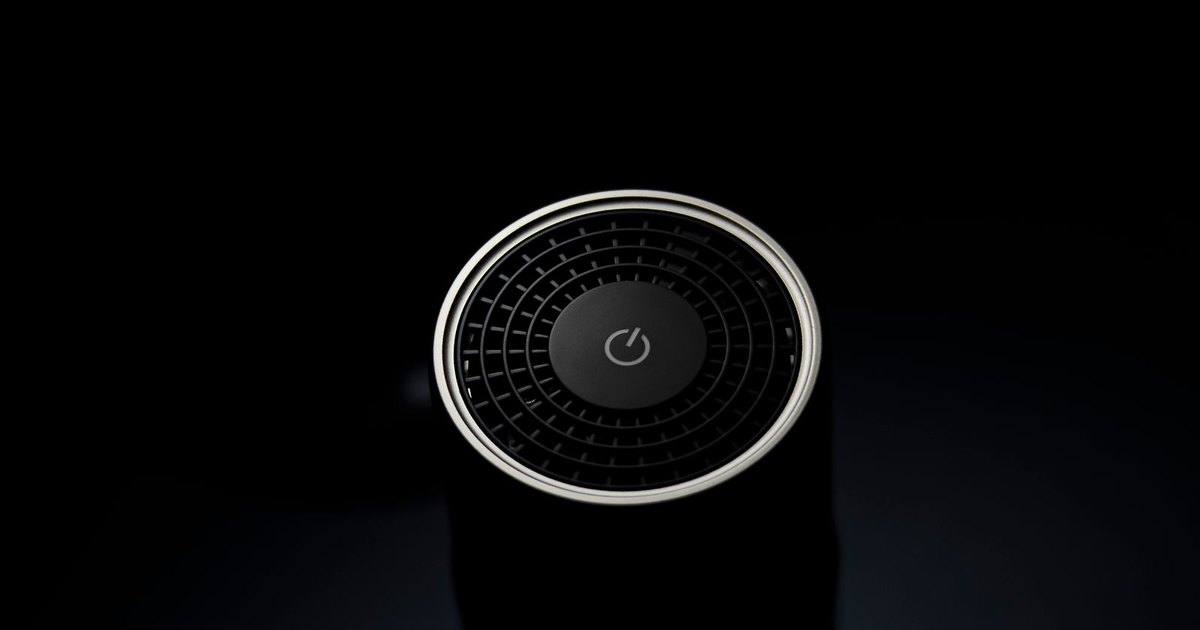 An air purifier running in a bright living room with a plant nearby