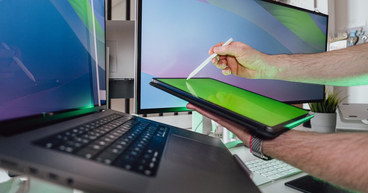 A portable monitor displaying vibrant colors next to a laptop on a travel desk